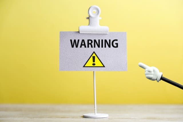 クリップに「WARNING」と書かれたメモが挟まれているのを指し棒で指している